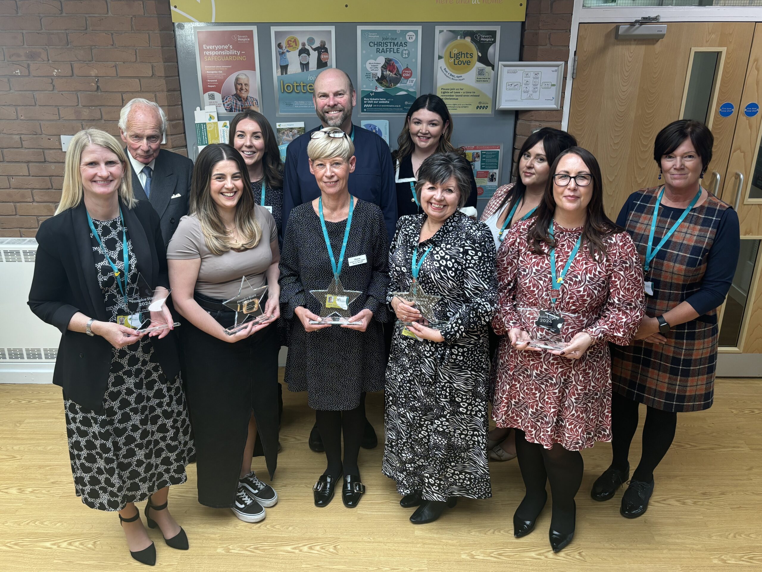 Staff standing in group with with winners holding star shaped glass trophies