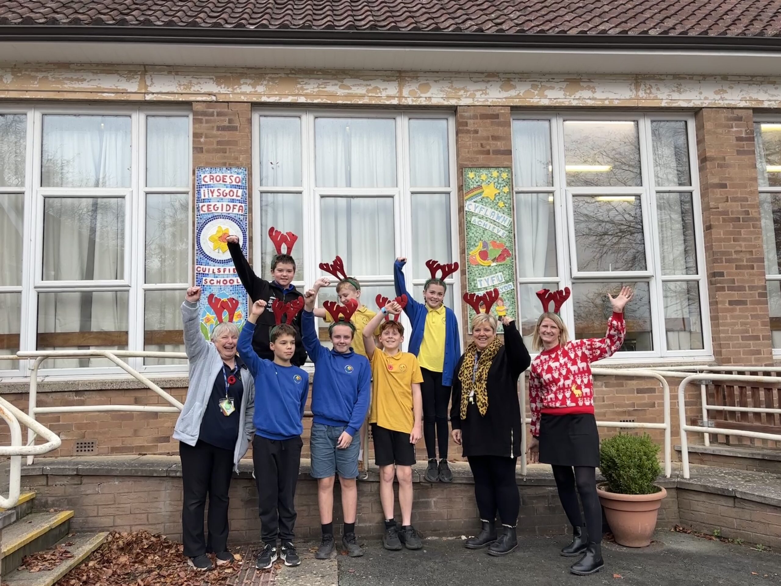 Two teachers, Severn Hospice fundraiser and school children pose with antlers in front of Guilsfield Primary School.