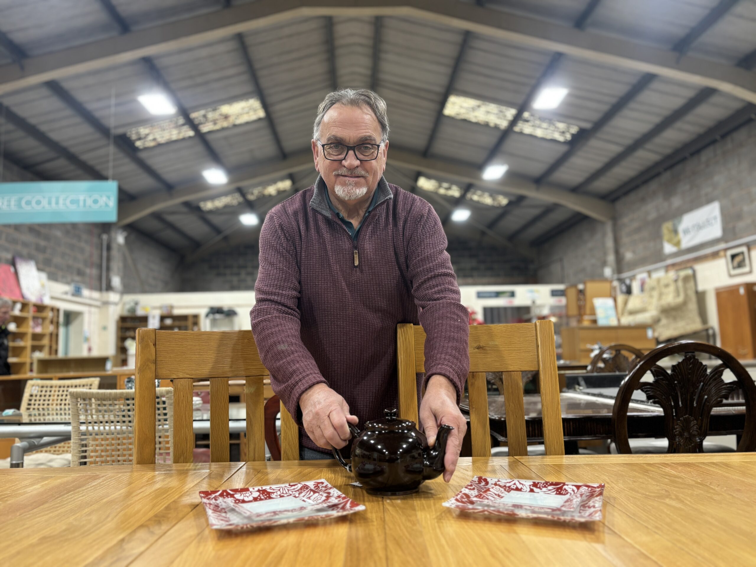 Volunteer placing teapot on table in shop